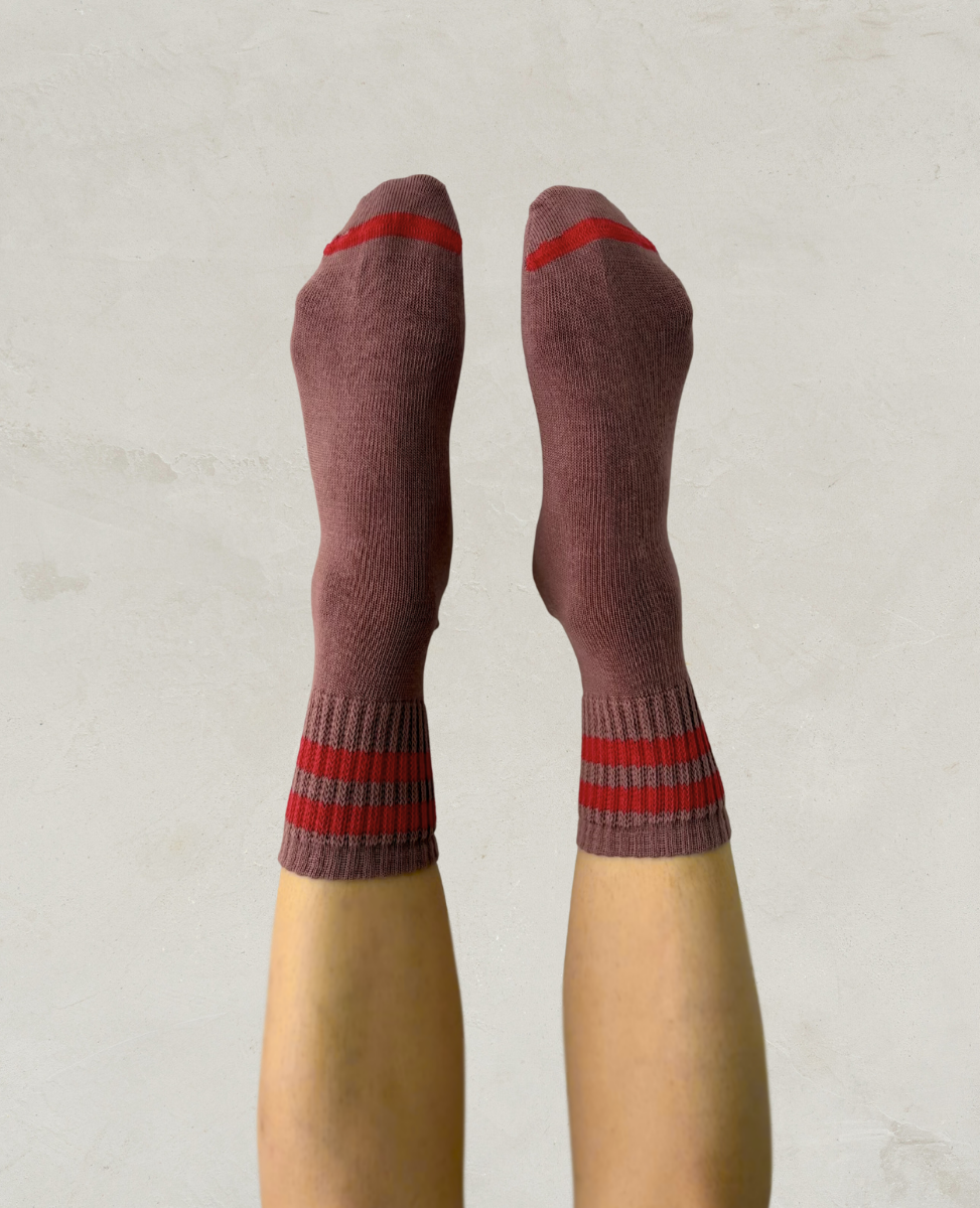 Escuyer Purple socks with red stripes worn by a person on a light gray background