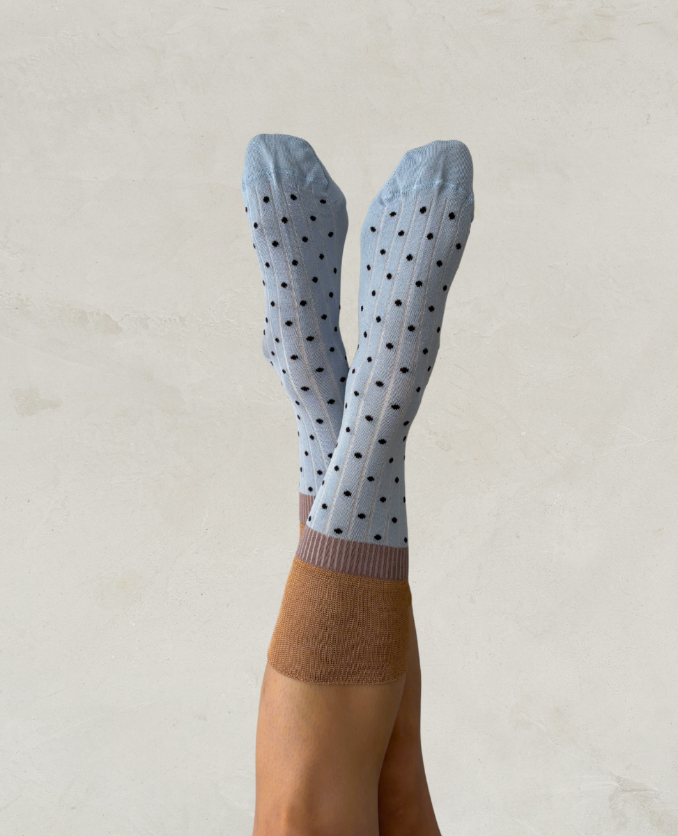 Exquisite J light blue socks with black polka dots worn by a person against a neutral background