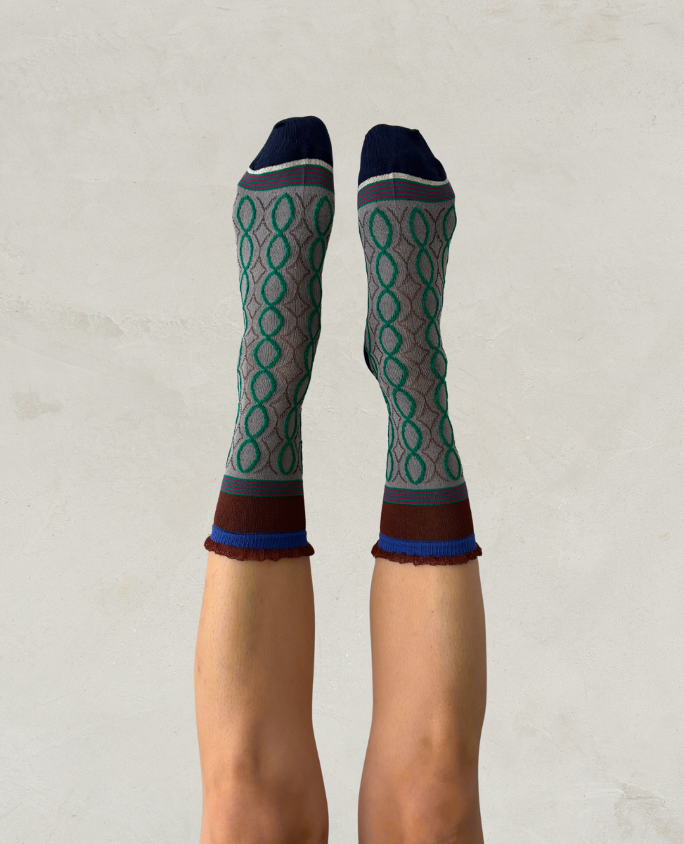 Exquisite J Patterned socks worn by a person on a plain background
