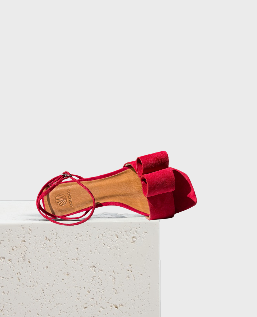 Red suede sandals with looped bow detail at front and ankle strap