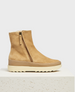 A tan suede ankle boot with a side zipper, a cream and beige rubber sole, and a minimalist design, featuring shearling lining and a slightly elevated platform. 1