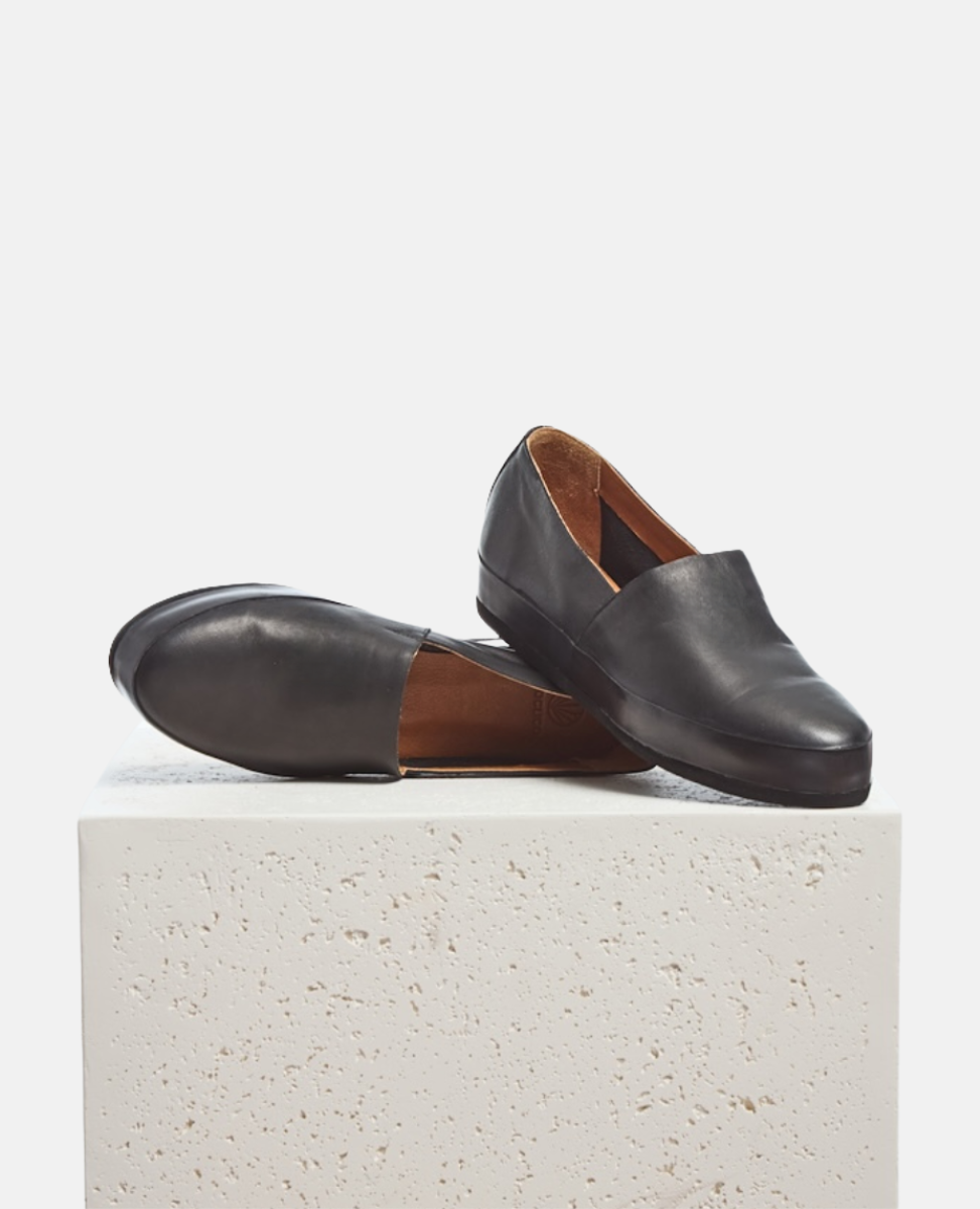 Pair of black leather loafers on a light gray background