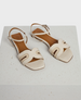 modern cream patent sandals with a layered arched front strap and quater strap buckle closure 1