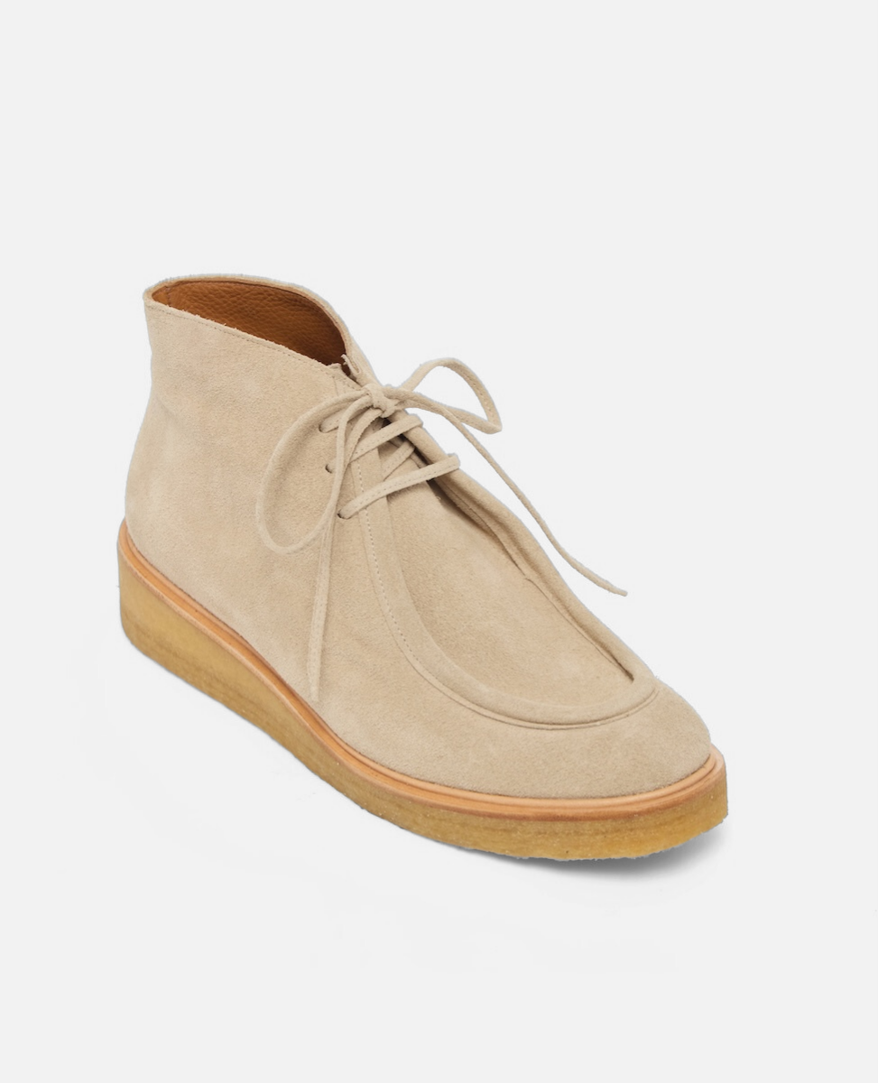 Beige suede shoe with brown sole on a white background