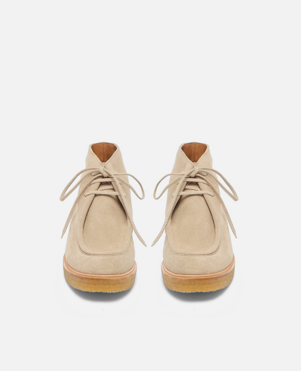 Pair of beige suede shoes with brown soles on a white background
