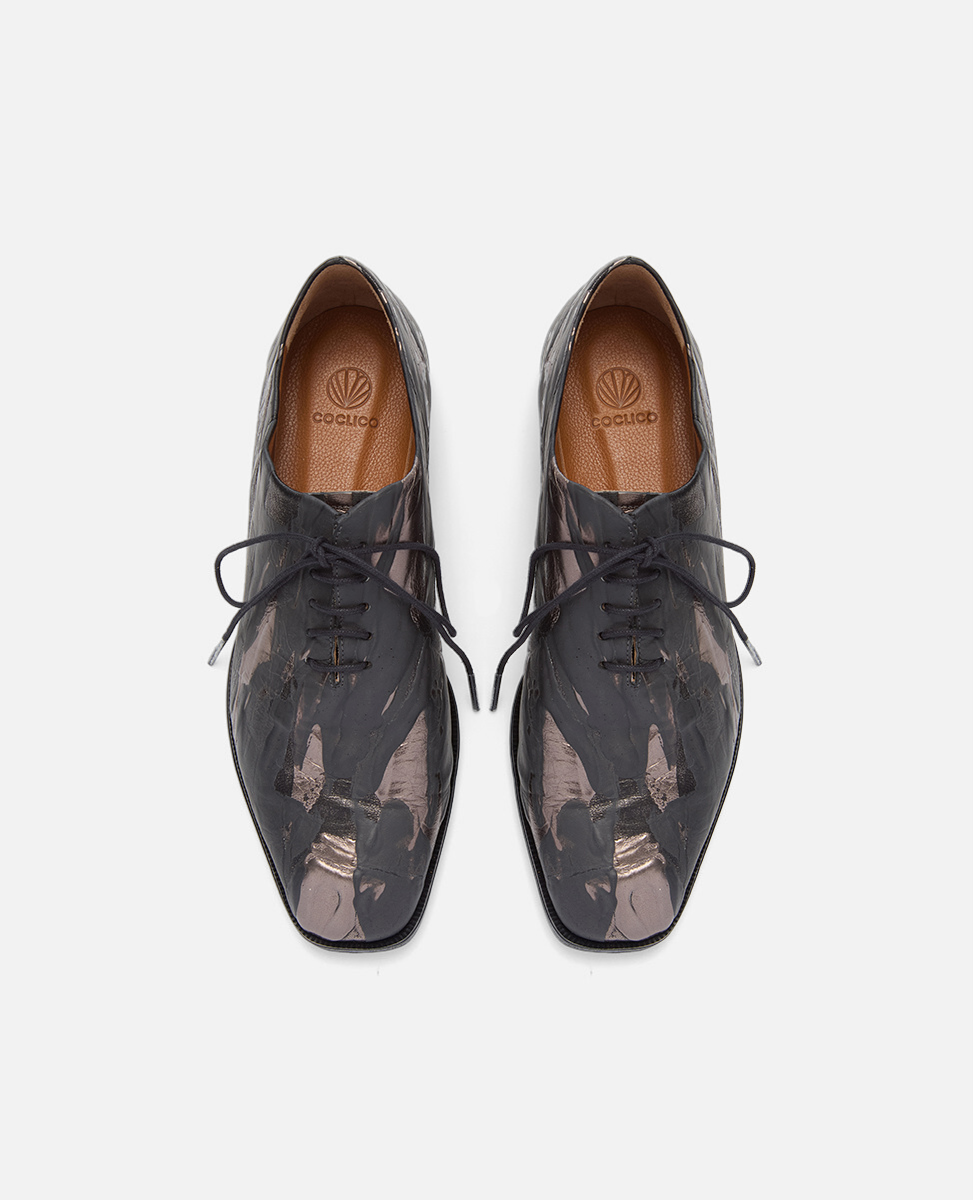 Pair of black leather shoes with abstract design on a white background