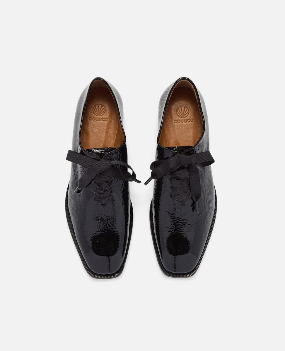 Pair of black patent leather shoes on a white background