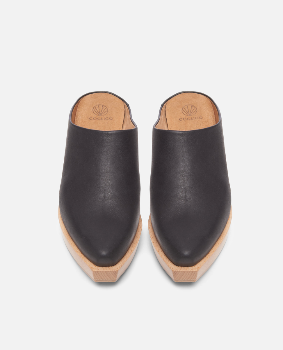 Pair of black leather clogs on a light gray background