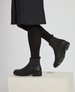 A pair of sleek, black ankle boots with a smooth leather finish, elastic side panels, a pull tab at the back, and a sturdy, slightly chunky sole. 3