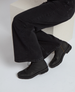 Black leather ankle boots with a smooth finish, lace-up design, and a low, sturdy heel, worn with dark, wide-leg pants. 5