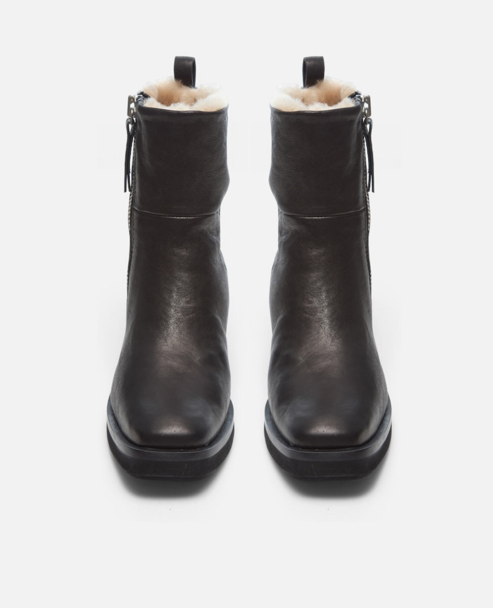 Pair of black leather boots with fur lining on a white background