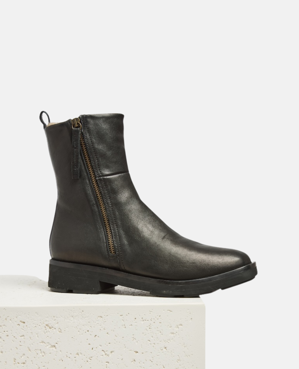 Black leather boot with a zipper on a light gray background
