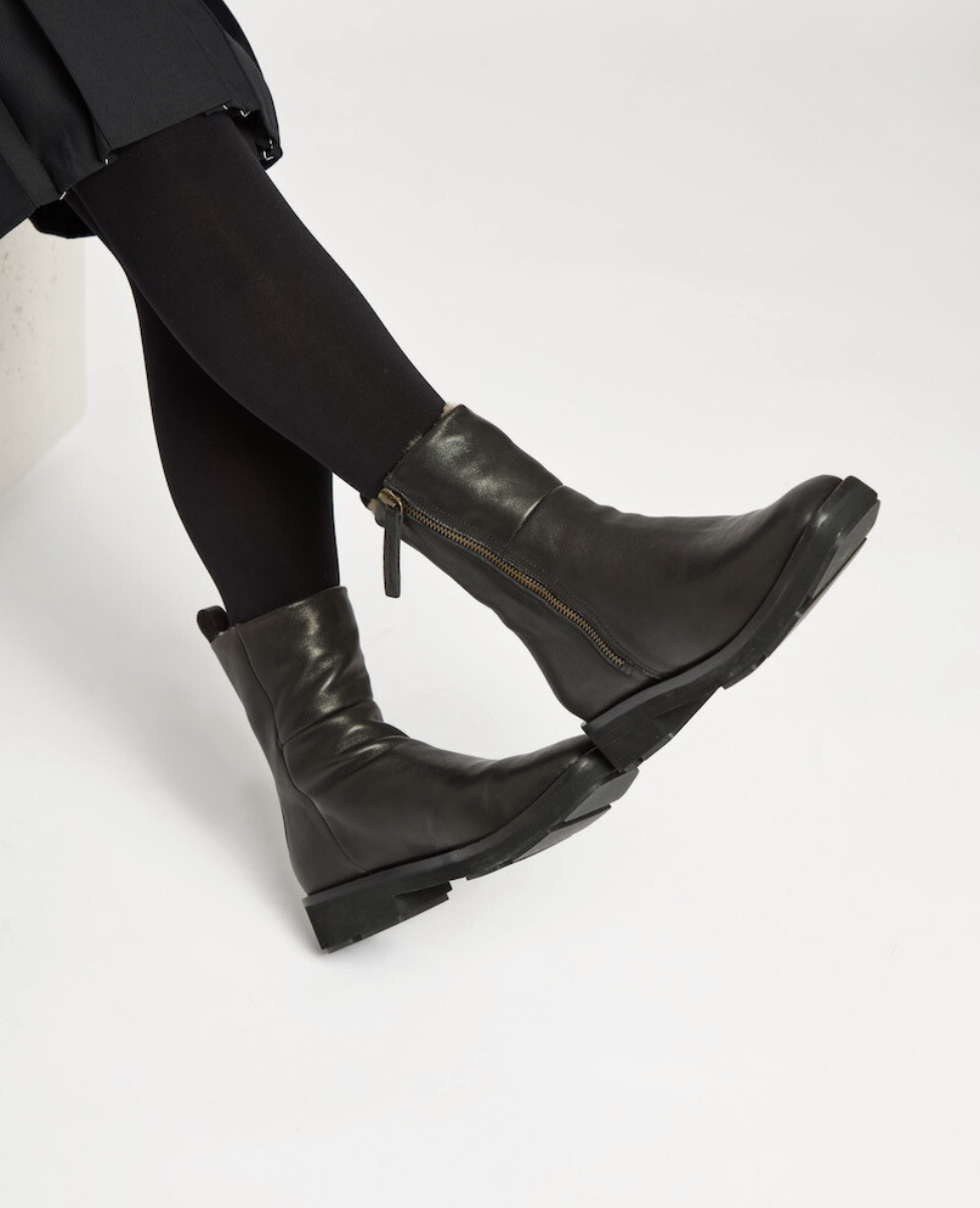 Black leather ankle boots with a side zipper, a slightly rounded toe, a chunky low heel, and a smooth, polished finish. Shearling Lined.