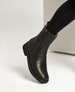 A sleek, black shearling lined boot with a side zipper, and a slightly squared toe. 3