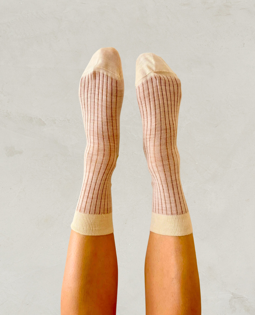 Beige knee-high socks with a subtle pattern worn by a person on a light gray background