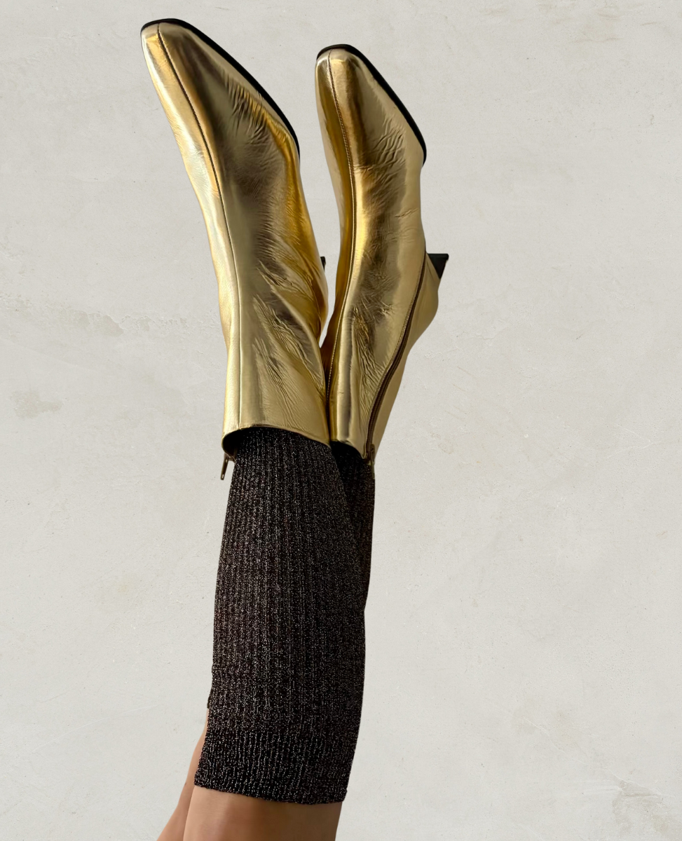 Gold high-heeled boots worn with brown glitter socks on a neutral background