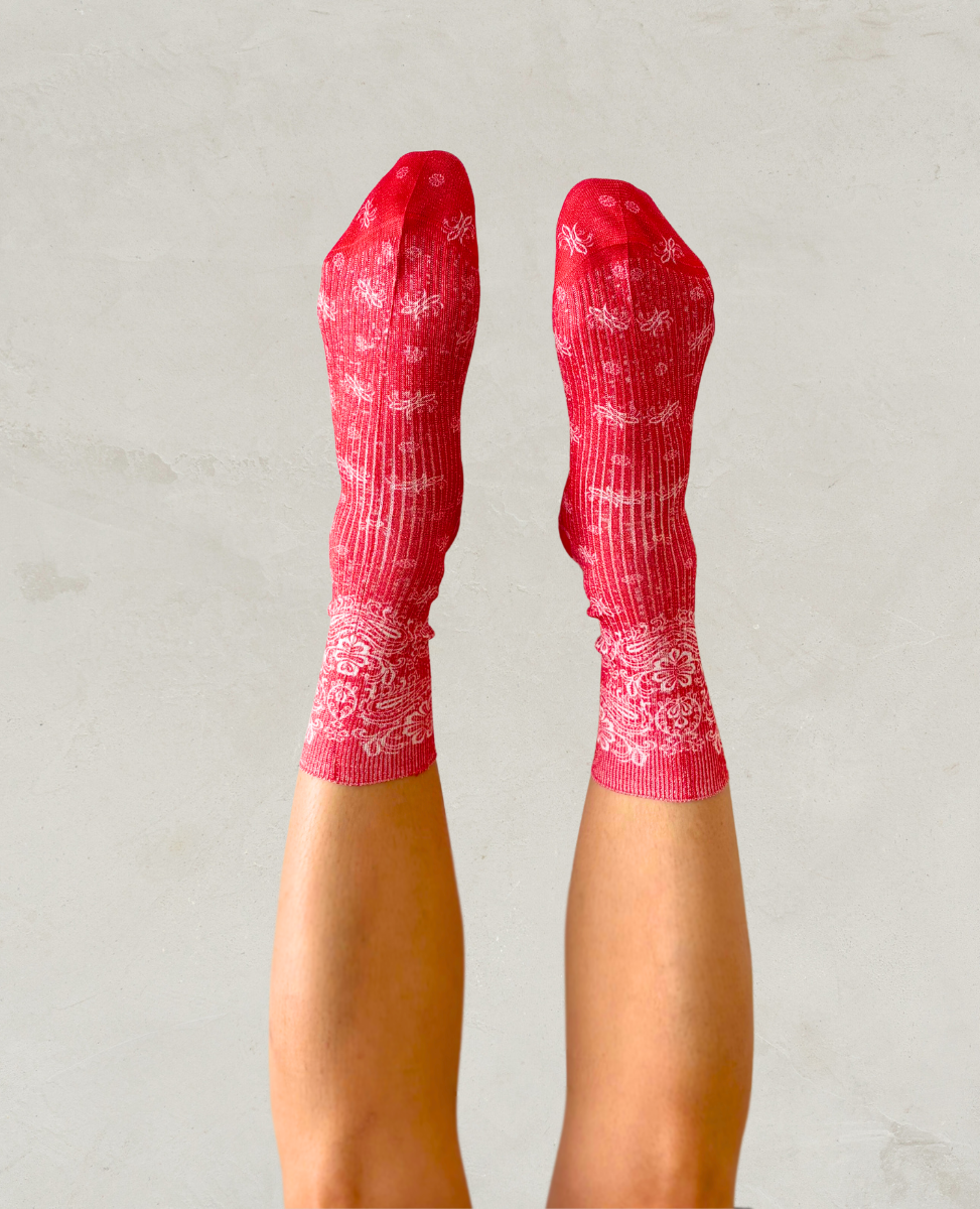 Pair of red socks with white paisley bandana pattern shown on the foot