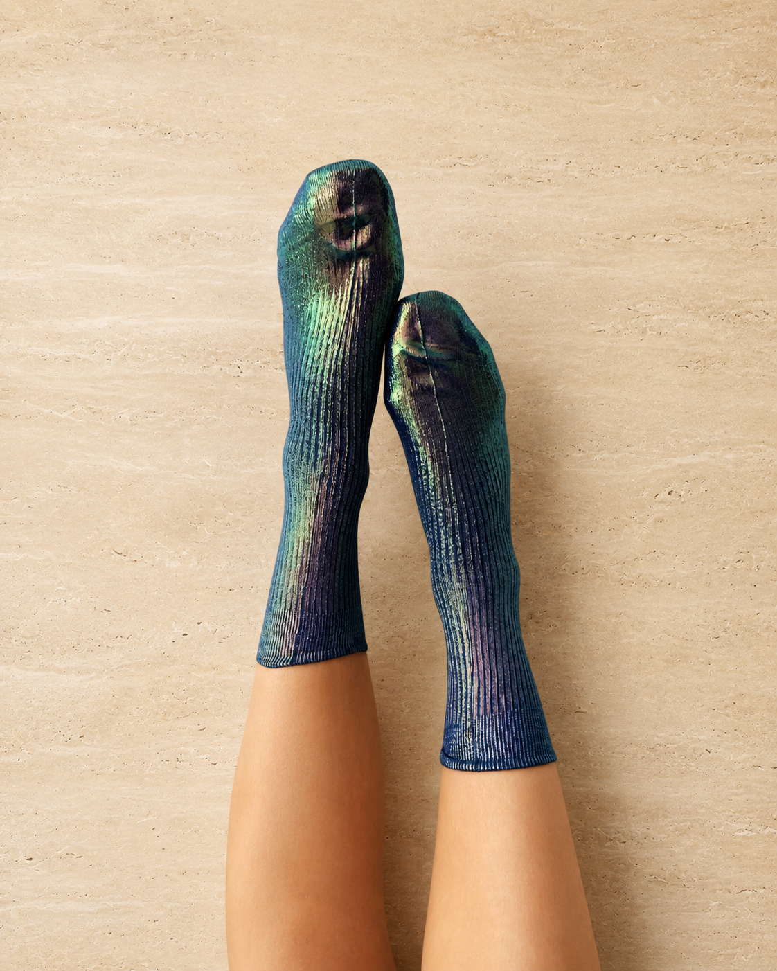A pair of iridescent socks with a ribbed texture, displaying a gradient of blue, green, and purple hues, worn on feet against a neutral background.