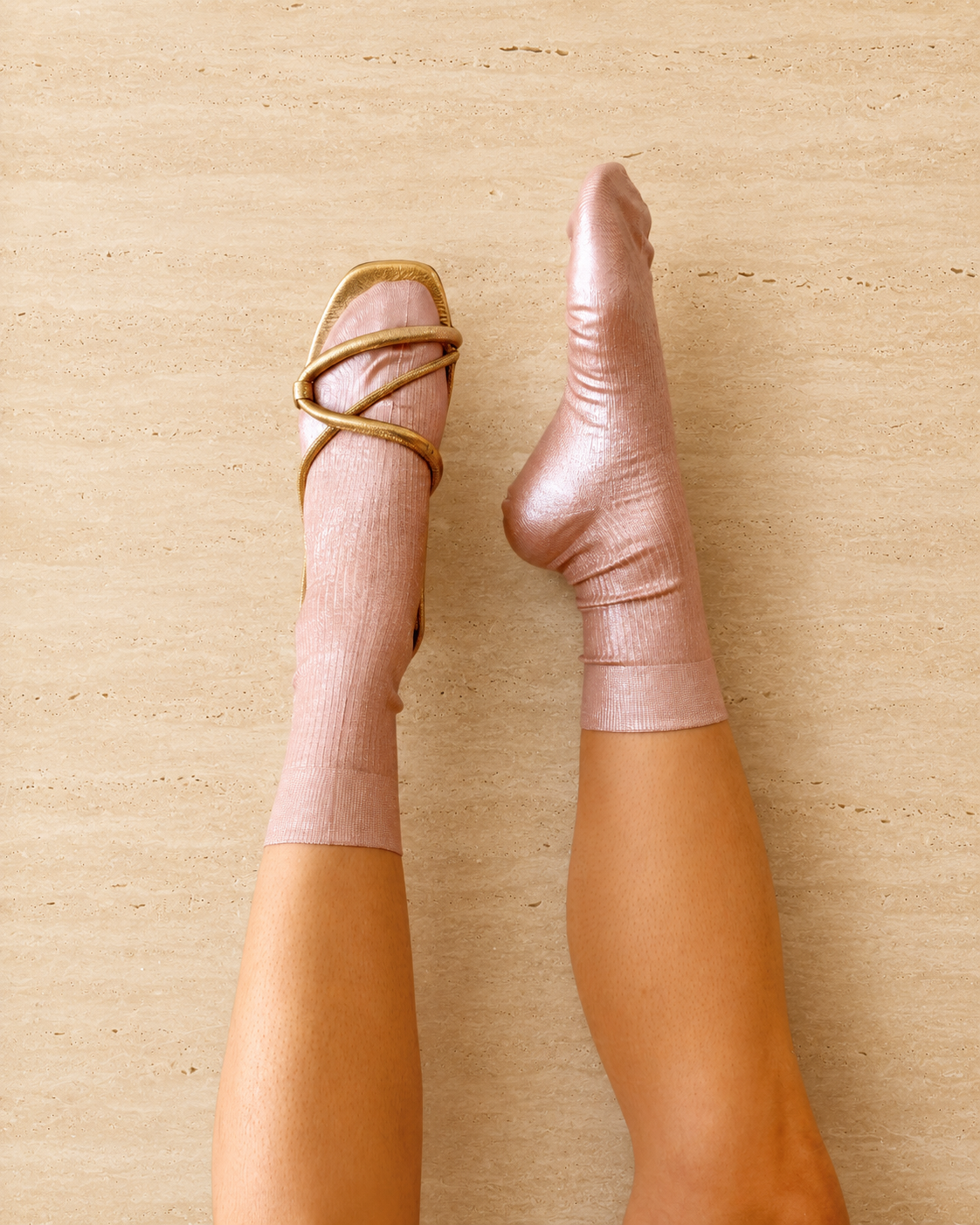 Pair of metallic foil pale pink silk socks by Maria La Rosa shown on the foot with a Coclico gold sandal