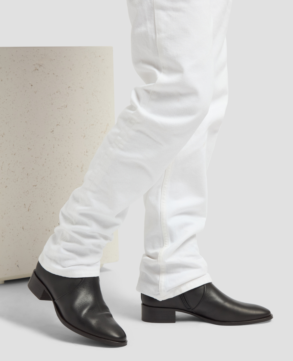 Black leather shoes worn with white pants on a light background