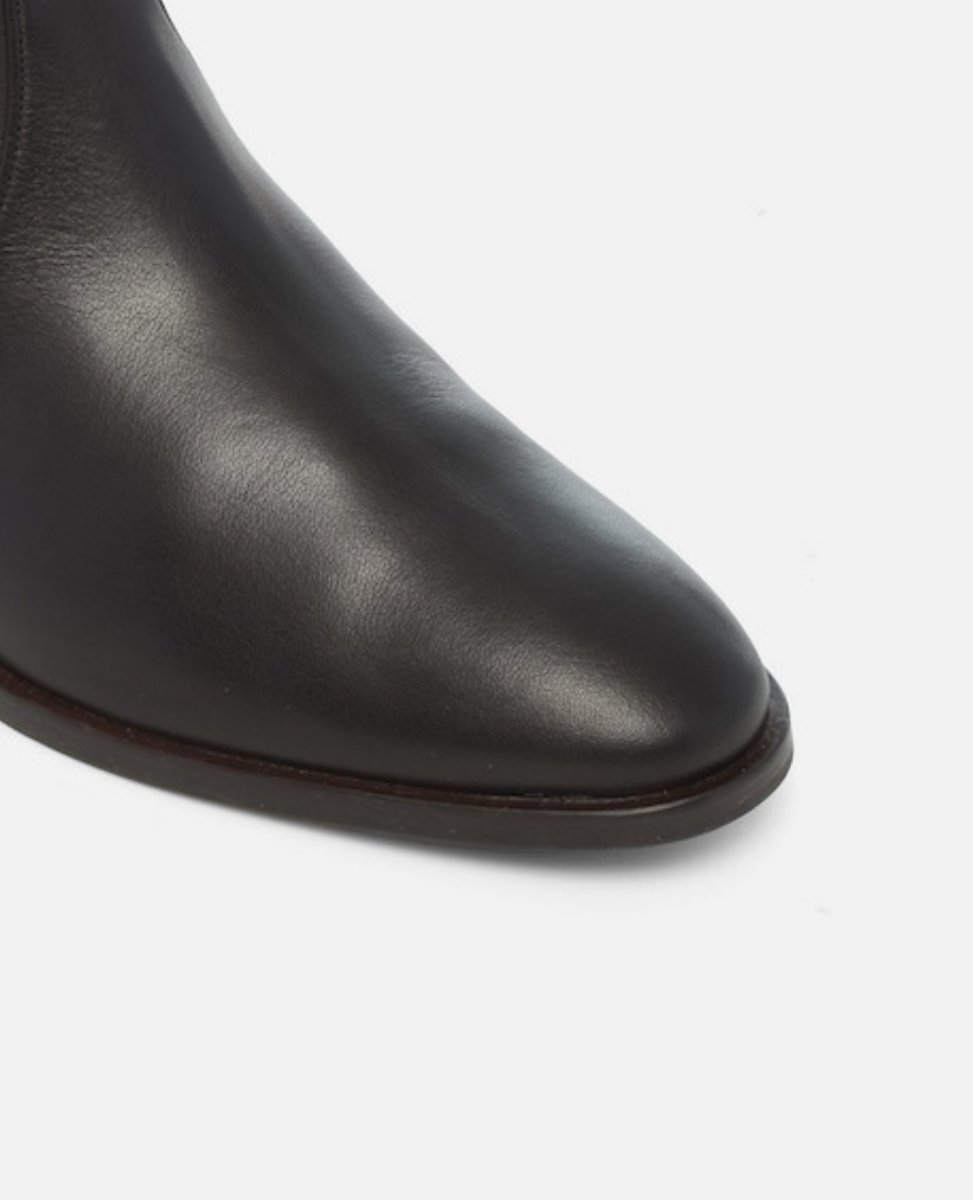 Close-up of a black leather boot on a white background