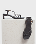 A pair of sleek black sandals with a square toe, thin straps, and a low block heel, featuring a minimalist design and smooth leather texture. 1