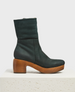 A mid-calf, dark blue nubuck leather boot, featuring a chunky wooden heel and platform, a side zipper, and a rounded toe. 1