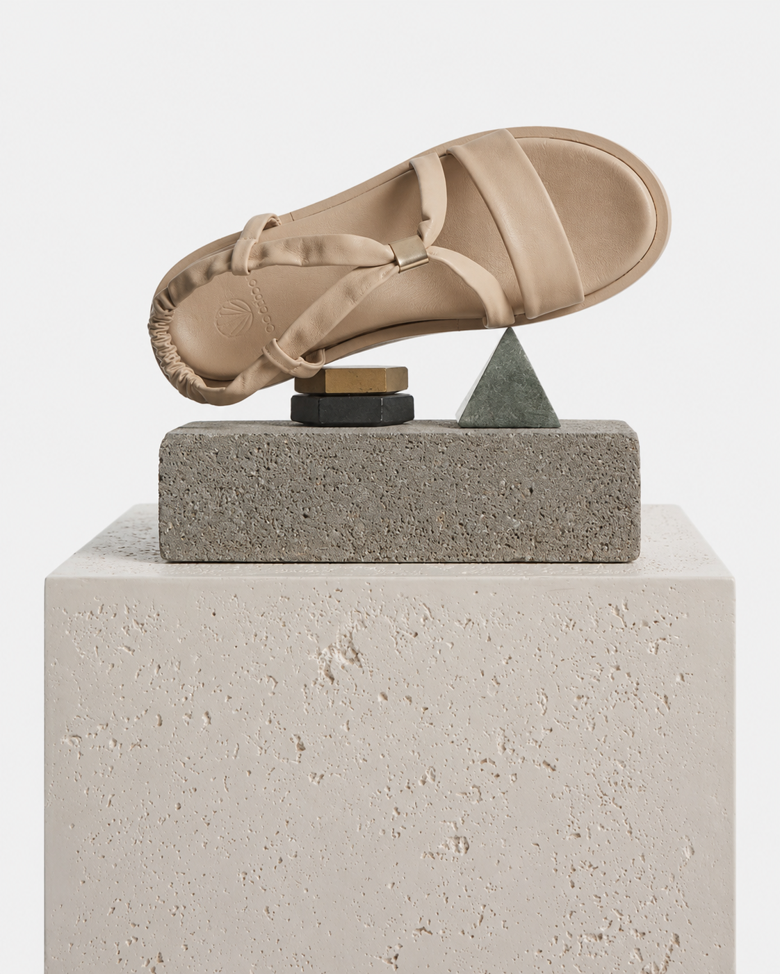 Beige sandal balancing on a geometric stone sculpture