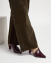 A pair of dark brown, wide-legged corduroy pants paired with glossy, burgundy pointed-toe wood-heeled shoes. 3