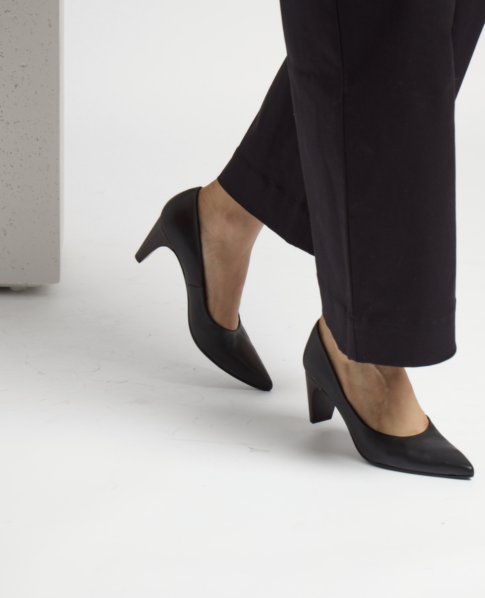 Black, pointed-toe, mid-heel shoes with a smooth leather finish, worn with black pants.