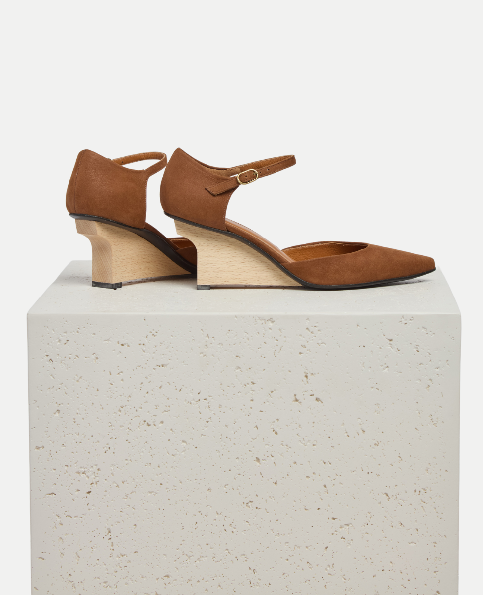 Pair of brown high-heeled shoes on a white pedestal