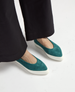 Teal suede flats with a pointed toe and a contrasting thick white rubber sole, worn with black pants. 2