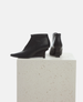 Black ankle boots on a light gray pedestal against a white background 3
