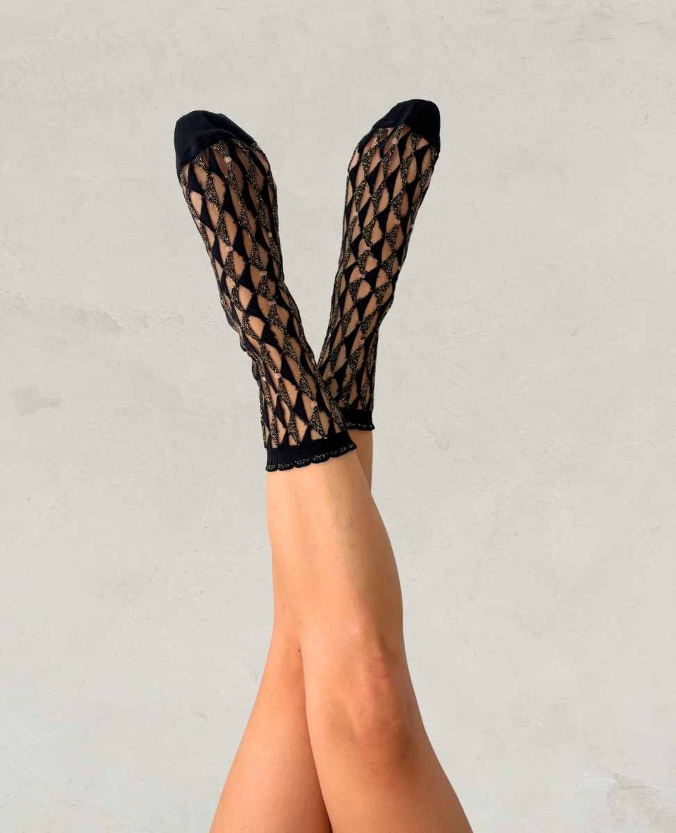 Black fishnet socks worn by a person on a light gray background