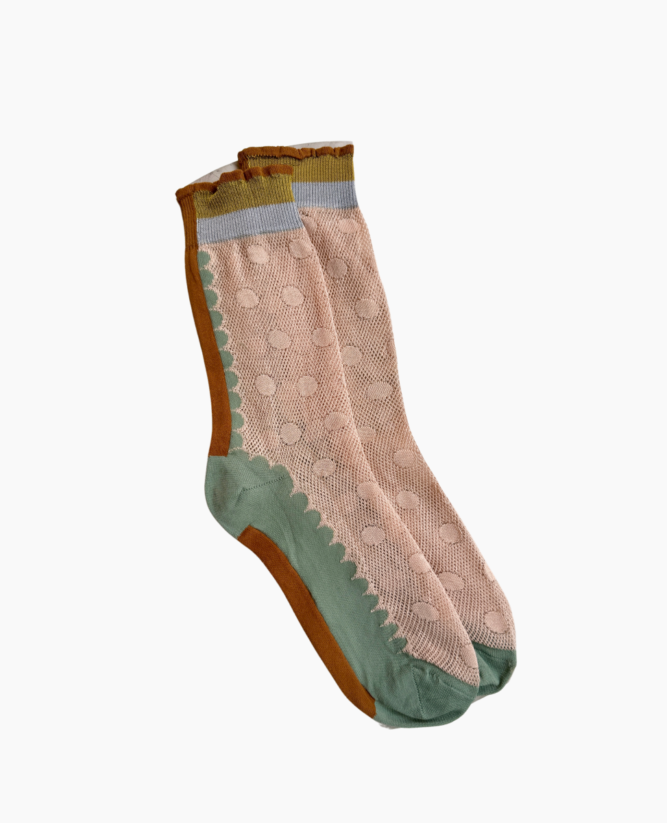 A pair of mid-calf socks featuring a pastel pink base with a textured polka dot pattern, accented by green and brown scalloped edges, and a light blue band at the top.