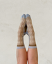 A pair of feet wearing socks with a beige and light brown checkered pattern, featuring light blue toes and cuffs, displayed against a neutral background. 1