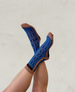 A pair of blue socks with a geometric pattern featuring light blue squares, brown toes, heels, and cuffs, made from a soft, stretchy fabric. 2