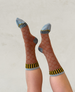 Sheer brown socks with a circular pattern, featuring light blue toes and heels, and black and yellow striped cuffs. 1