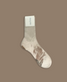 A single, light beige sock with a smooth texture, made from a soft, stretchy material, featuring a rectangular white label at the top with text. 2