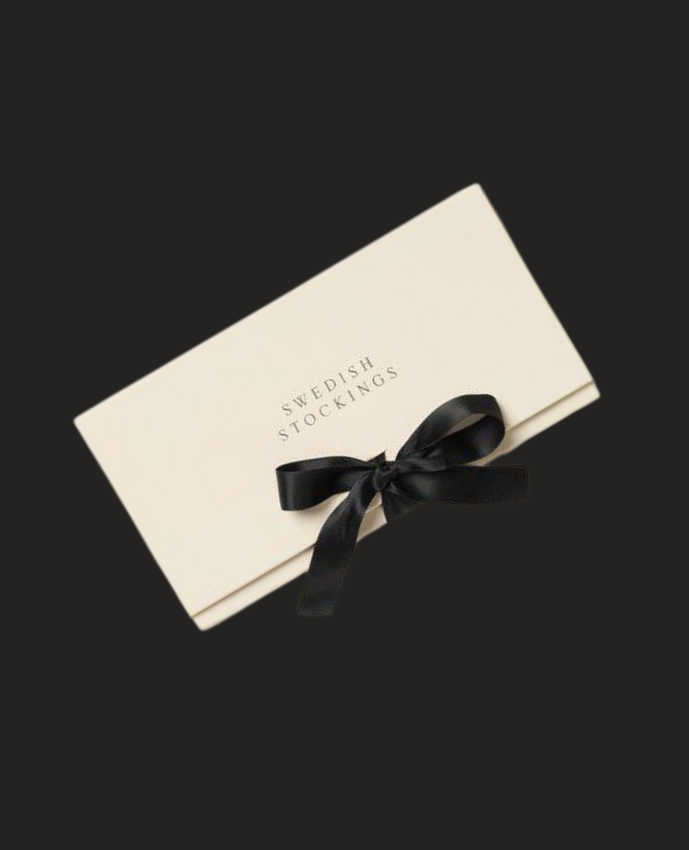 A rectangular, cream-colored box with the words "Swedish Stockings" printed in black on the lid, adorned with a sleek black ribbon tied into a bow.