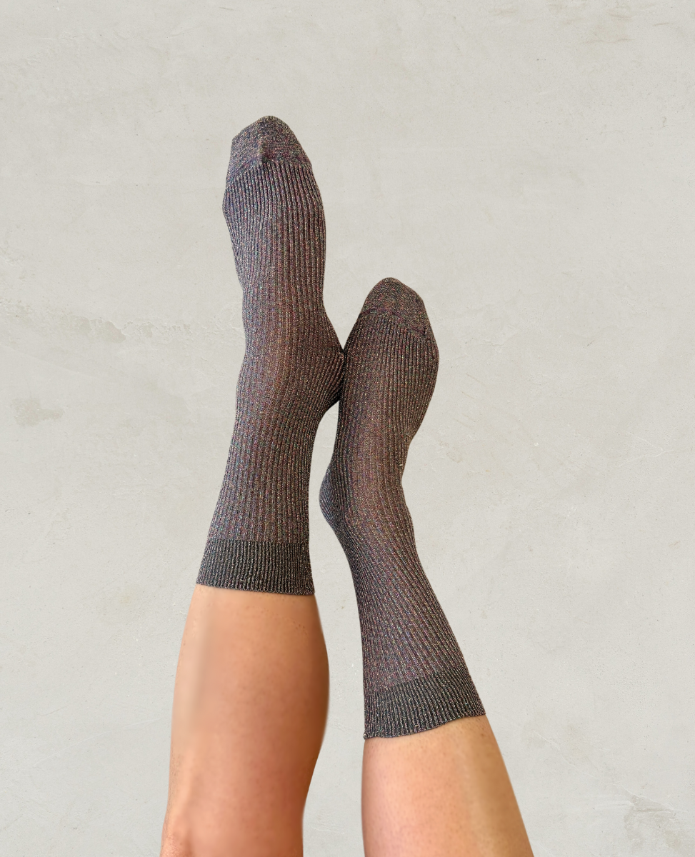 A pair of gray ribbed socks with a subtle striped pattern, featuring reinforced toes and cuffs, worn on crossed feet against a light background.