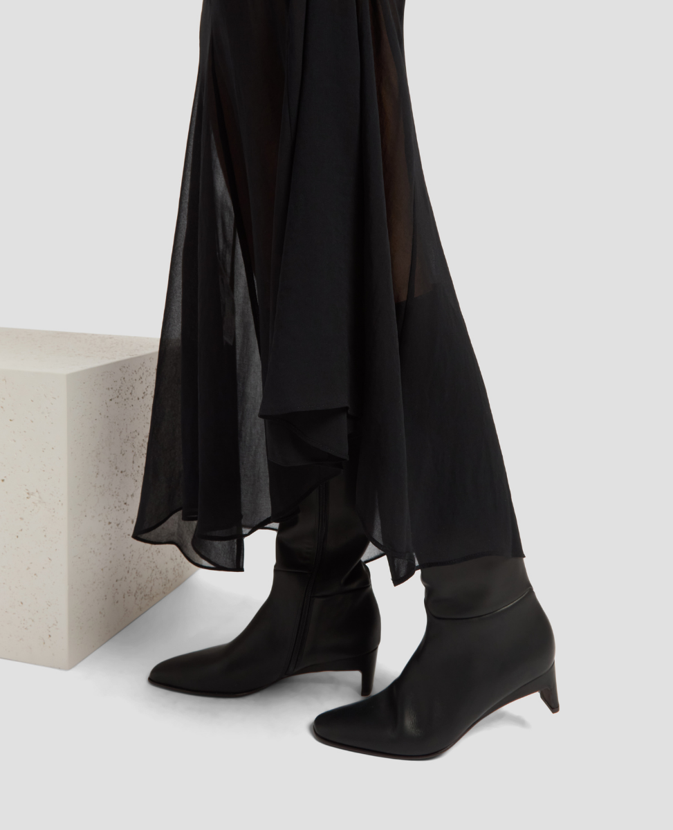 Person wearing black ankle boots with a plain background