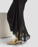 Black sheer skirt with gold high-heeled shoes on a light gray background 6