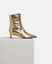 Gold metallic ankle boot on a white pedestal with a white background 4