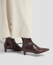 Brown leather ankle boots worn with a cream sweater on a light gray background 7