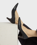 Sleek black leather pumps with a pointed toe, mid-height block heel, and smooth finish, showcasing a minimalist and elegant design. 1