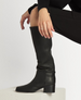 A sleek, knee-high black leather boot with a smooth texture, featuring a rounded toe, a low block heel, and a subtle seam running vertically along the side. 1