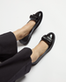 Shiny black leather ballet flats feature a rounded toe, a sleek bow detail on top, and a smooth, glossy finish, complementing their simple, elegant design. 3