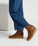 Brown leather ankle boots with a smooth texture, featuring a rounded toe, a side zipper, and a thick, light brown rubber sole, worn with blue denim jeans. 2