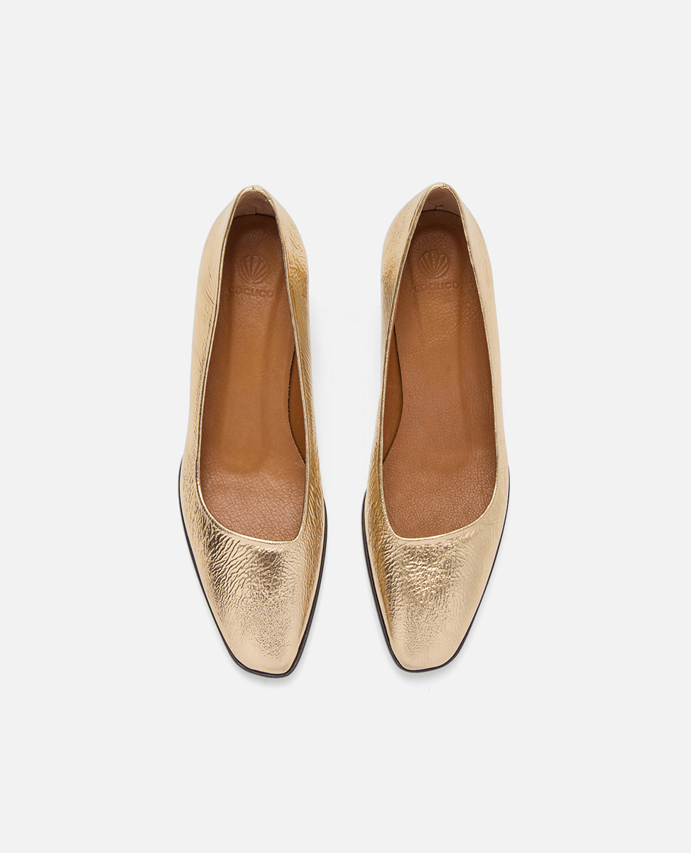 Pair of gold metallic shoes on a white background